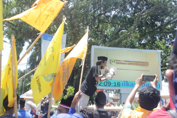 alah seorang orator menaiki pagar Kantor Gubernur, karena tidak kunjung diizinkan masuk setelah dua jam massa aksi menunggu di gerbang Kantor Gubernur Sumbar, Senin (1/3/2021). (Genta Andalas/Geliz Luh Titisari)