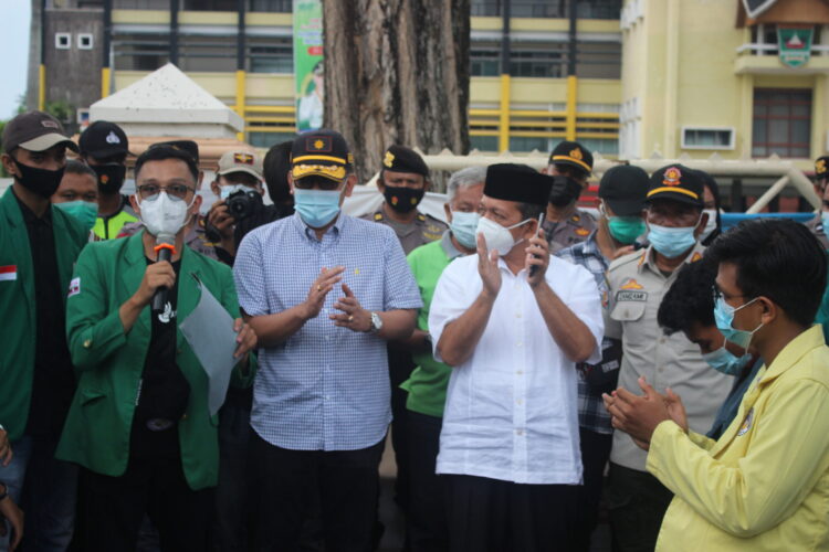 Wapresma Unand Dafiq Naskar bacakan tuntutan dalam aksi Tolak UU Cipta Kerja disaksikan oleh Kepala Disnakertrans Sumbar, Nasrizal di depan Kantor Gubernur Sumbar, Sabtu (1/5/2021). (Genta Andalas/Afdal Hasan)