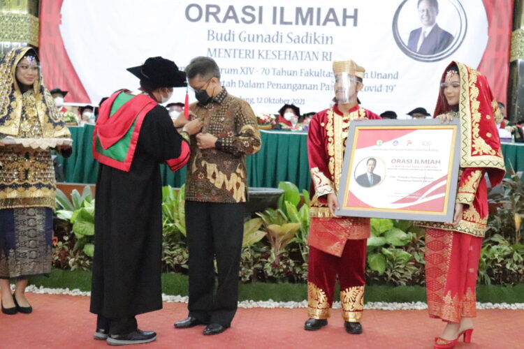 Pemasangan pin Fakultas Hukum Unand oleh Dekan Fakultas Hukum kepada Menteri Kesehatan Budi Gunadi Sadikin di Convention Hall Universitas Andalas pada Selasa (12/10/21). (Genta Andalas: Geliz Luh Titisari)