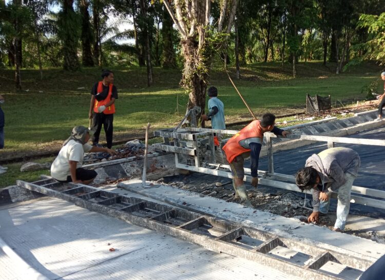 Beberapa orang pekerja sedang melakukan perbaikan jalan Gerbang-Bundaran Rektorat Unand pada Jumat (15/10/21). (Genta Andalas/ Natasya Salsabilla Festy)