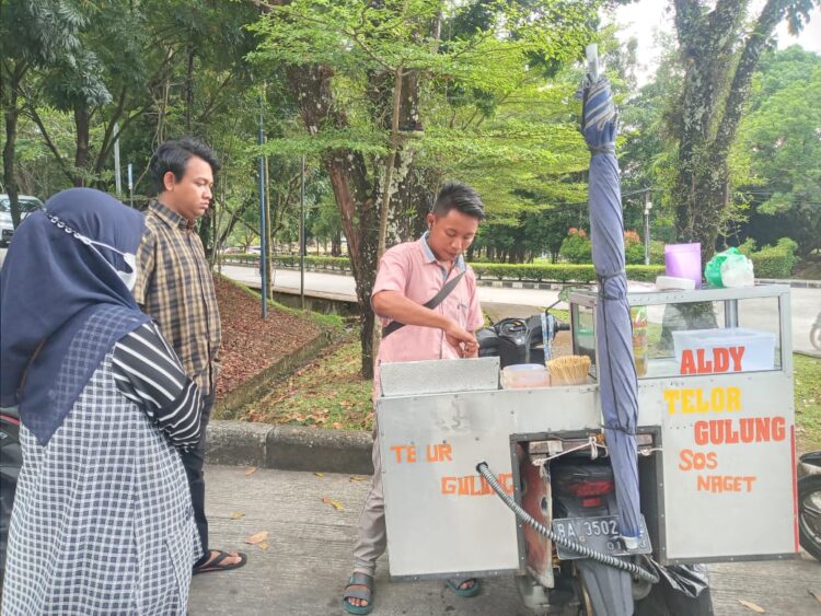 Pedagang Kaki Lima (PKL) yang sedang melayani pembeli dari kalangan mahasiswa di lingkungan bank sentral Universitas Andalas (Unand), Rabu (2/3/2022)