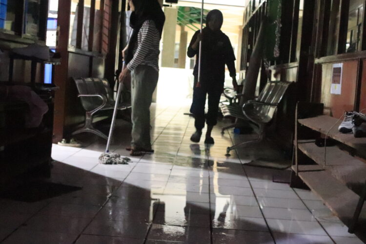 Mahasiswa sedang mengepel lantai yang digenangi air akibat kebocoran atap PKM, Sabtu (13/8/2022). (Genta Andalas/Geliz Luh Titisari)
