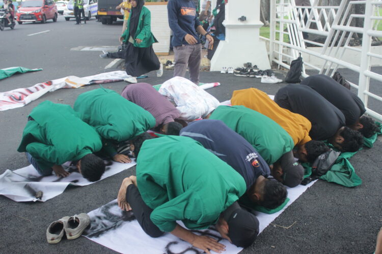 Mahasiswa peserta aksi melaksanakan salat berjamaah di depan gedung Gubernur Sumatra Barat, Senin (26/09/2022). (Genta Andalas/Fatiza Khaira)