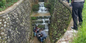 Warga mengevakuasi satu unit sepeda motor yang jatuh ke dalam parit saat kecelakaan, Jumat (16/09/2022). (Genta Andalas/M. Rivaldo)