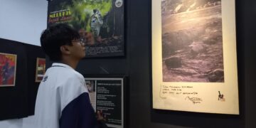 Salah seorang pengunjung sedang melihat jepretan foto yang dipamerkan pada pameran fotografi Tribute to 5AW, Sabtu (21/1/2023) (Genta Andalas/Bilqis Zehira Ramadhanti Ishak)