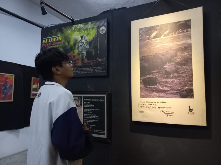 Salah seorang pengunjung sedang melihat jepretan foto yang dipamerkan pada pameran fotografi Tribute to 5AW, Sabtu (21/1/2023) (Genta Andalas/Bilqis Zehira Ramadhanti Ishak)