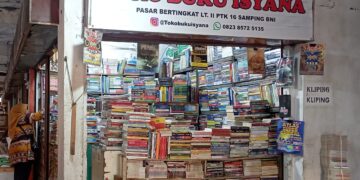 Penjual toko buku bekas, Vivi sedang merapikan buku-buku bekas tokonya di gedung oranye lantai dua Pasar Raya Padang, Minggu (2/4/2023) (Aisyah Luthfi/Genta Andalas)