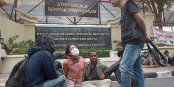 Mahasiswa yang dijadikan contoh bentuk penyiksaan oleh aparat kepolisian yang dipaksa untuk mengaku atas perbuatannya dalam menyuarakan suara rakyat di depan kantor Polda Sumbar, Senin (26/6/2023) (Genta Andalas/Fahara Azzah Syafaqoh)
