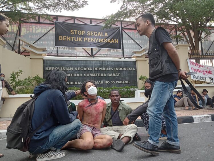 Mahasiswa yang dijadikan contoh bentuk penyiksaan oleh aparat kepolisian yang dipaksa untuk mengaku atas perbuatannya dalam menyuarakan suara rakyat di depan kantor Polda Sumbar, Senin (26/6/2023) (Genta Andalas/Fahara Azzah Syafaqoh)