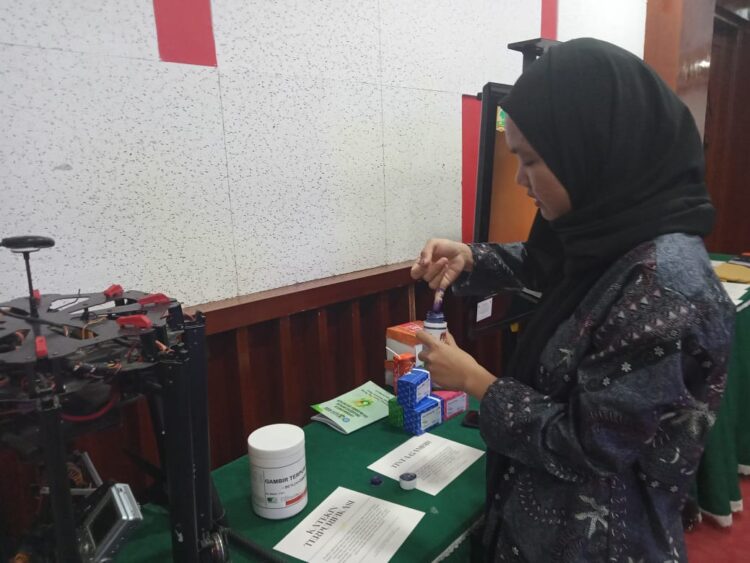Salah seorang pengunjung yang mencoba inovasi tinta organik dari gambir pada acara Dies Natalis UNAND di Convention Hall UNAND pada Rabu (13/09/2023). (Genta Andalas/Atika Liutami Sadri)