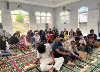 Suasana penuh kehangatan dalam acara santunan anak yatim yang diadakan di dalam masjid. Anak-anak dan pengurus LMJ duduk bersama di atas sajadah, mendengarkan dengan penuh perhatian.