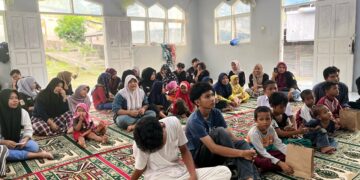 Suasana penuh kehangatan dalam acara santunan anak yatim yang diadakan di dalam masjid. Anak-anak dan pengurus LMJ duduk bersama di atas sajadah, mendengarkan dengan penuh perhatian.