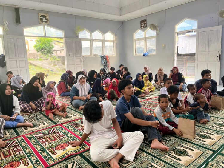 Suasana penuh kehangatan dalam acara santunan anak yatim yang diadakan di dalam masjid. Anak-anak dan pengurus LMJ duduk bersama di atas sajadah, mendengarkan dengan penuh perhatian.