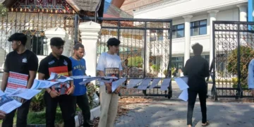 Koalisi Masyarakat Sipil membentangkan deretan kertas berisi catatan kasus kekerasan dan penyiksaan oleh aparat kepolisian Sumbar di depan Gedung DPRD, Kamis (26/06/25) (Genta Andalas/Alizah Fitri Sudira)