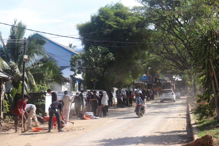 Terlihat mahasiswa KKN Kebencanaan UNAND memadati Jalan Simpang Pasia, untuk membersihkan sisa lumpur dan sampah pascabanjir Sabtu (6/12/2025) (Genta Andalas/Pitri Yani)