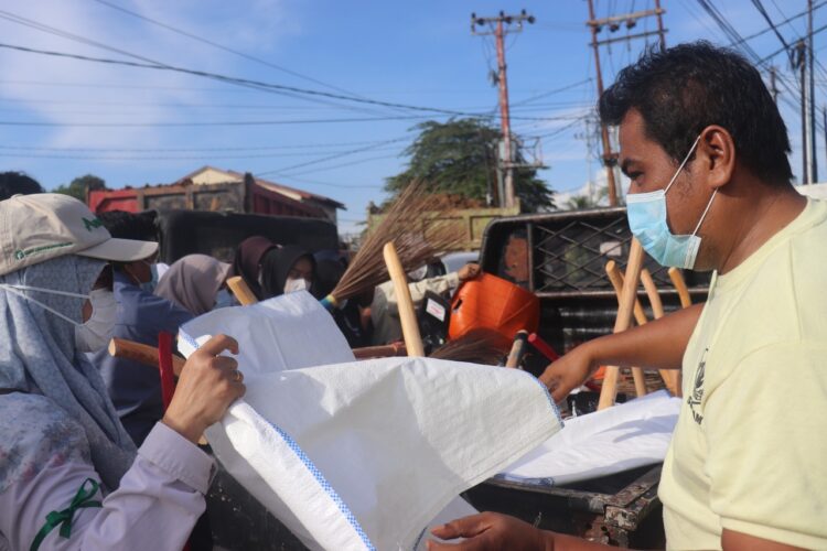 Satpam UNAND membagikan peralatan kebersihan kepada Mahasiswa KKN Kebencanaan dan relawan di kawasan Simpang Pasia, Padang, saat kegiatan gotong royong pascabanjir. Sabtu (6/12/2025) (Genta Andalas/Pitri Yani)